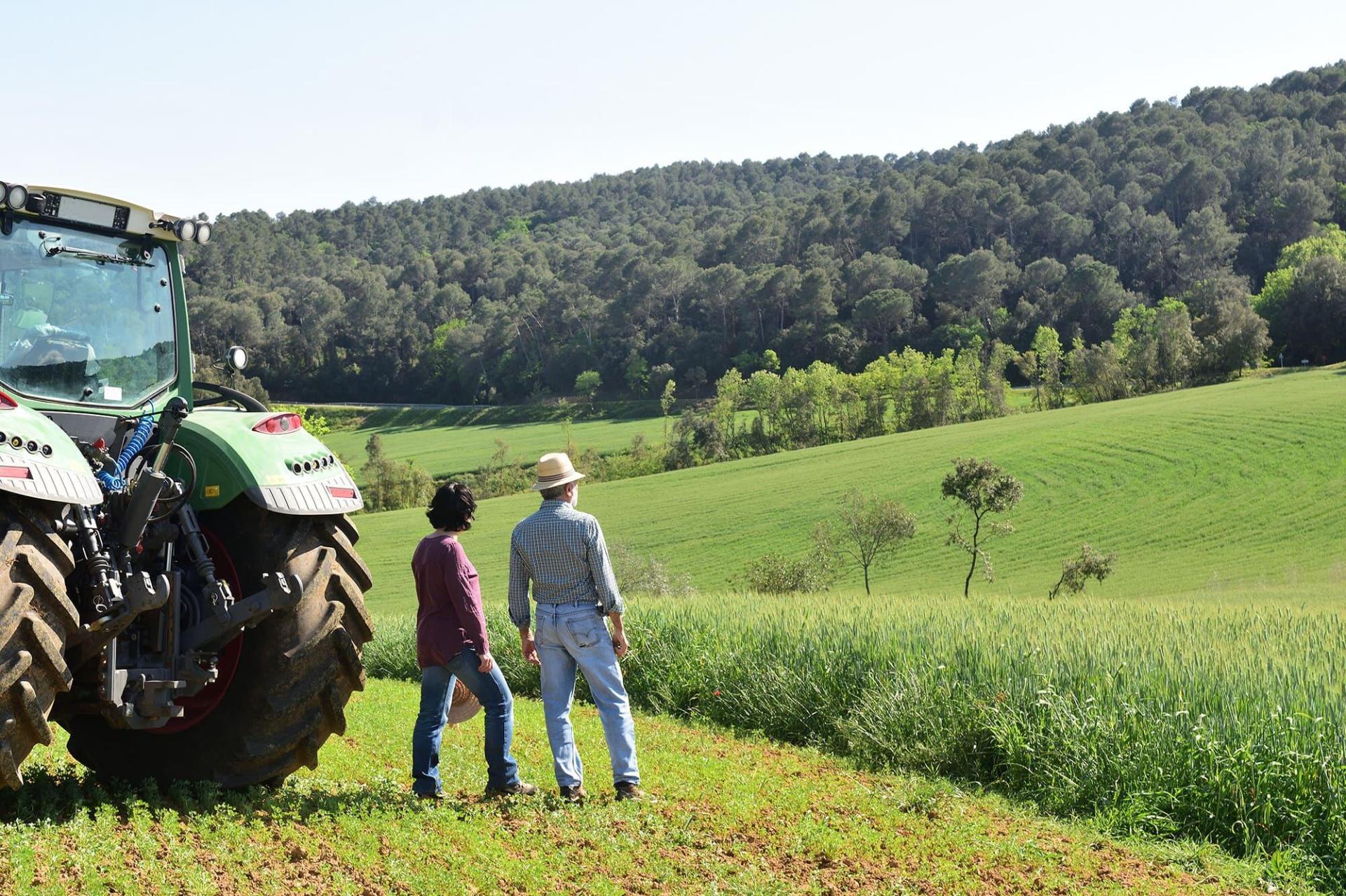 couple d'agriculteurs dans un champs et tracteur